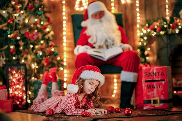 Funny girl in Santa hat writes letter to Santa