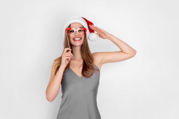 Funny girl in santas hat wears pretend hearts glasses isolated on white background new year party