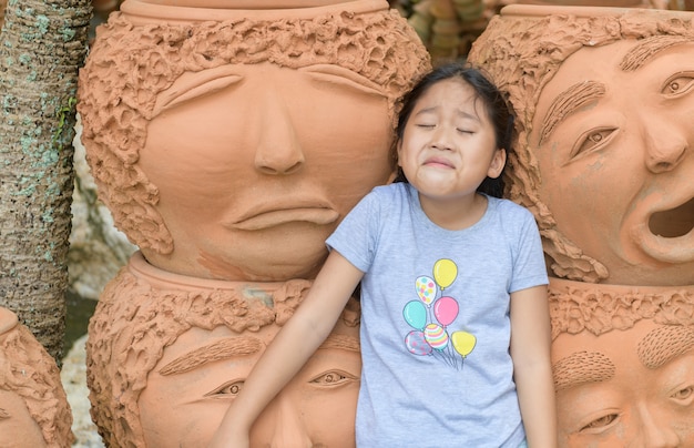 Ragazza divertente che mostra grido o emozione triste vicino a vasi di terracotta,