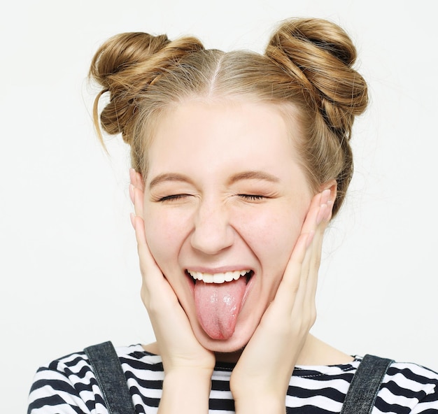 Funny girl showing her tongue while posing against studio background