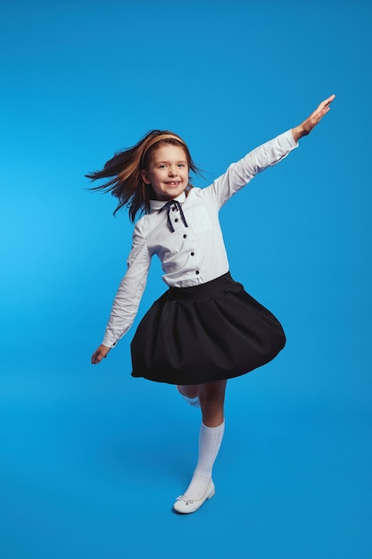 Funny girl spinning fast in school uniform dress causing it to flare out