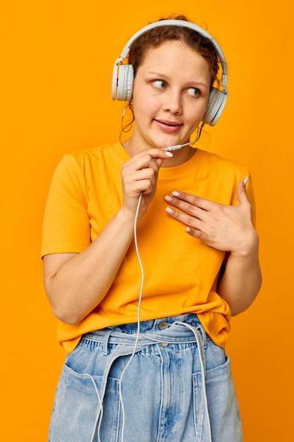 Funny girl wearing headphones denim shorts closeup emotions yellow background unaltered