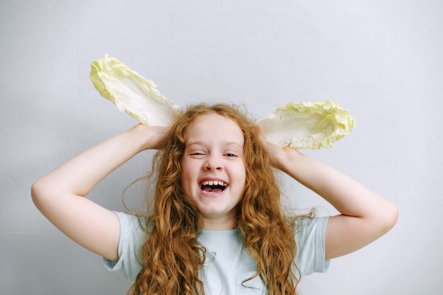 Photo funny girl with ears of peking cabbage.