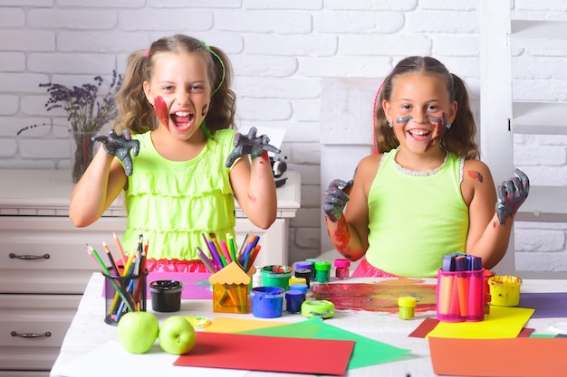 Funny girls children painters painting with gouache paints