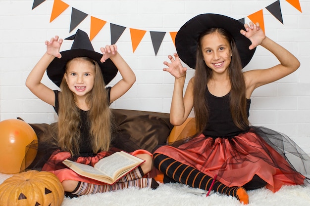 Funny girls in witch costumes for Halloween scare making scary faces