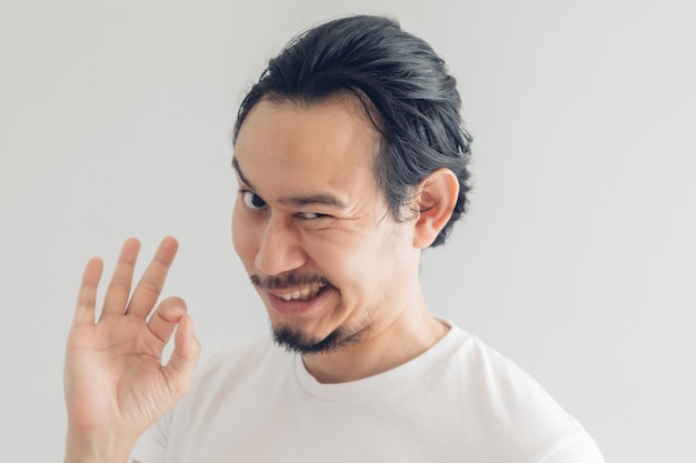 Funny grinning smile face of man in white t-shirt and grey background.