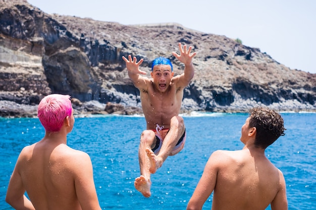 Funny group of friends having fun together at the beach pulling his friends to the water jumping