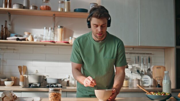 Photo funny guy cooking meal in earphones dancing kitchen closeup man listening music