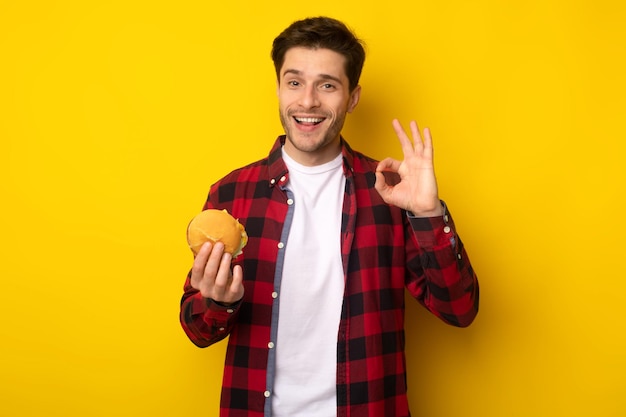 Funny guy holding burger showing okay gesture