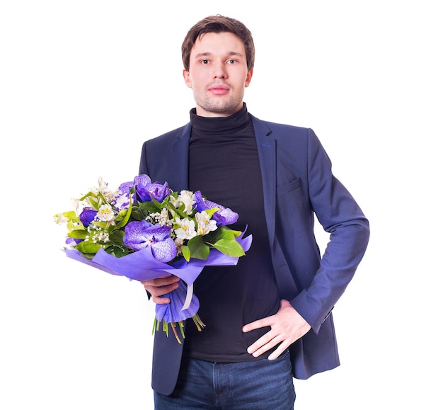 Funny handsome young man with dark suit with a beautiful bouquet in the hands of white and purple flowers isolated on a white background