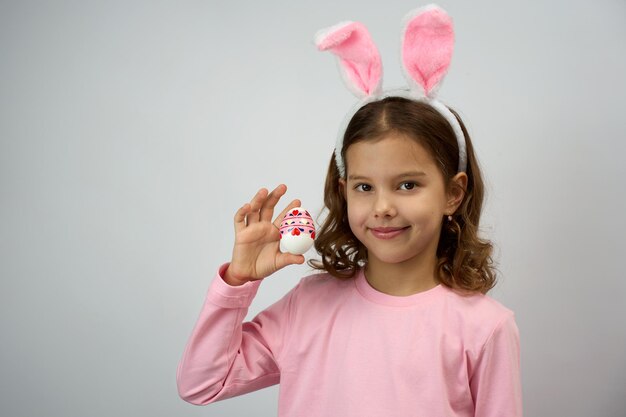 Foto una ragazza divertente e felice con uova di pasqua e orecchie di coniglio.