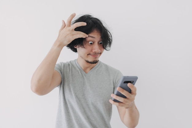 男の面白くて幸せな顔は白い背景の上の彼のスマートフォンを見てください