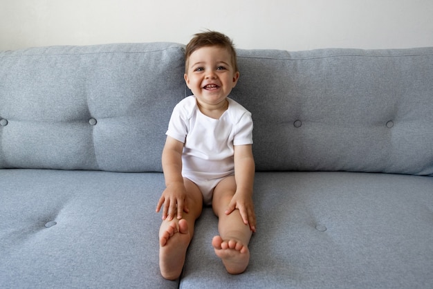 Divertente bambino sano e felice di un anno seduto sul divano di casa begli occhi i bambini giocano e il bambino...