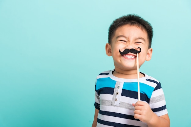 Funny happy hipster kid holding black mustache props