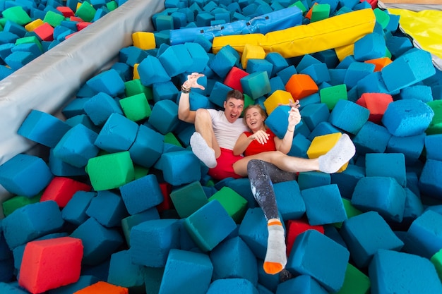 Funny happy man and woman having fun on a trampoline indoors