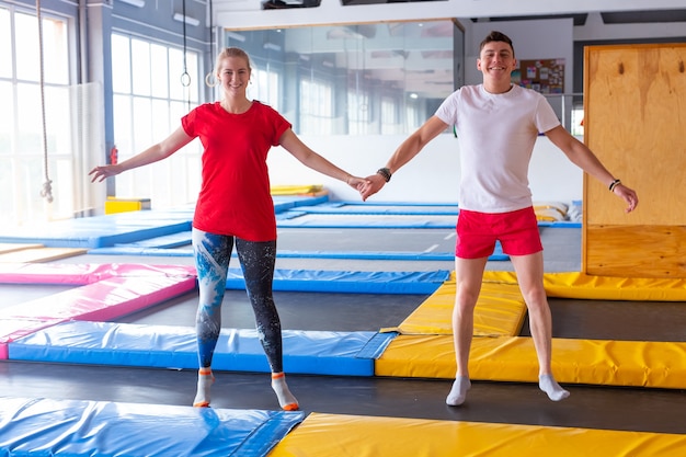 Funny happy man and woman jumping on a trampoline indoors