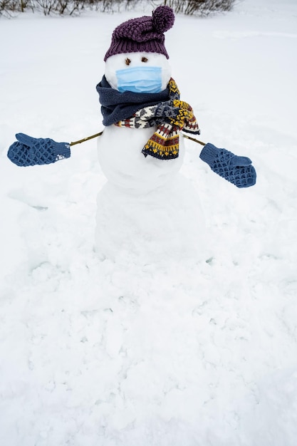 Funny homemade snowman in a medical mask hat scarf and mittens\
wants to cuddle