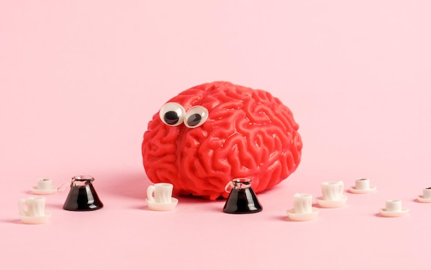 Photo funny human brain model with googly eyes and a lot of coffee cups benefits and harm o