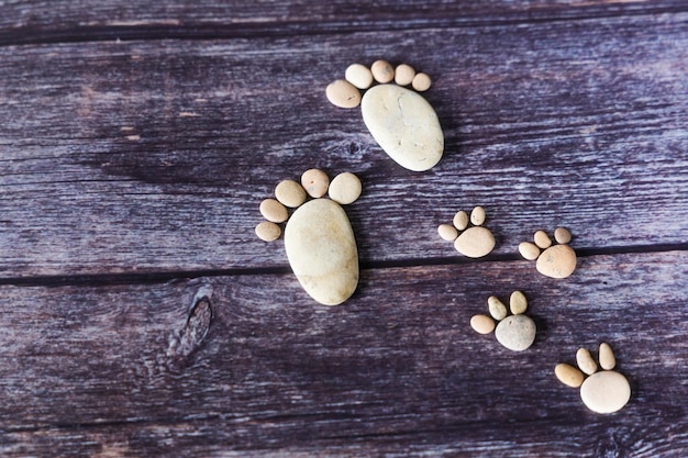 Funny human footprints from stones on a wooden background.