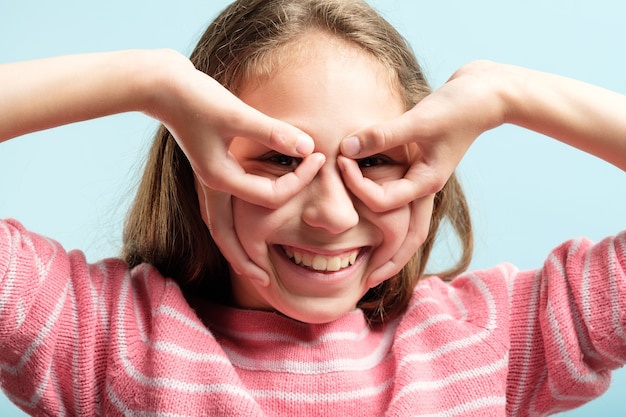 Funny joyful comic playful girl pretending to look through binoculars made of hands. emotional facial expression.