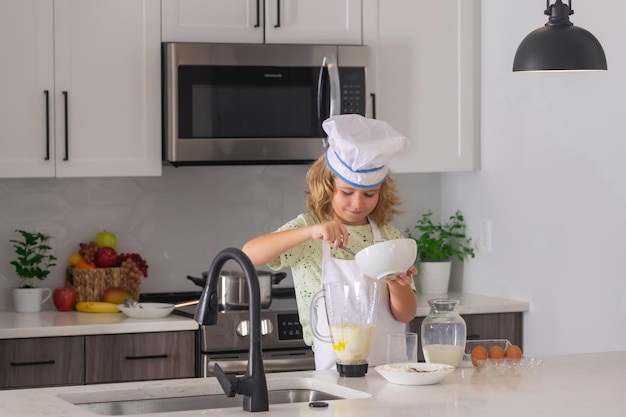 Funny kid chef cook cookery at kitchen Chef kid boy making healthy food Portrait of little child in chef hat