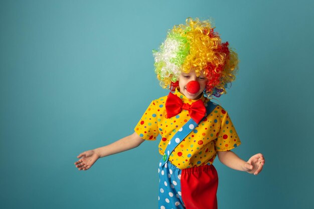 Funny kid clown against blue background Happy child playing with festive decor 1 April Fool's day