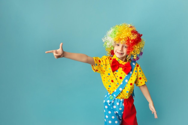 Funny kid clown against blue background Happy child playing with festive decor Birthday concept