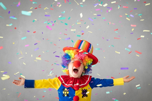 Funny kid clown against falling confetti.