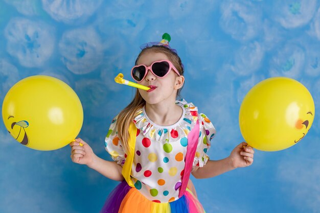 Photo funny kid clown playing against a bright wall 1 april fools day concept birthday concept