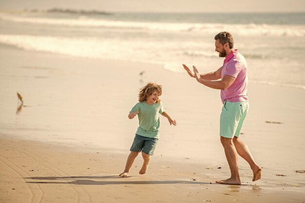 Foto bambino e papà divertenti che corrono sulla spiaggia durante le vacanze estive per allenarsi insieme