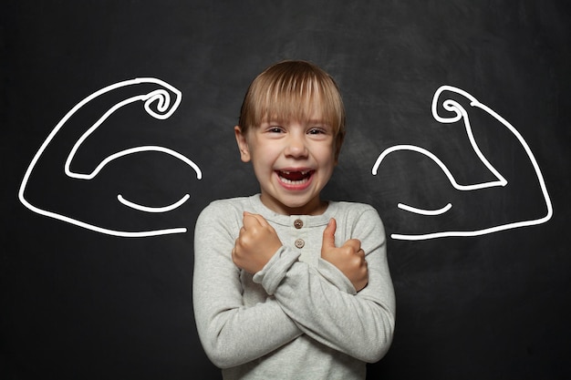Funny kid girl playing superhero laughing and having fun on black background