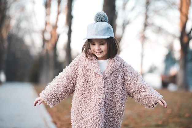 Funny kid girl wearing trendy winter coat in park