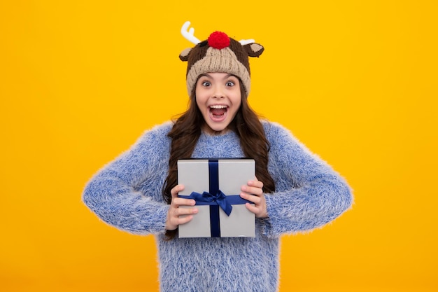 Funny kid girl in winter wear holding gift boxes celebrating\
happy new year or christmas winter holiday amazed teenager excited\
teen girl