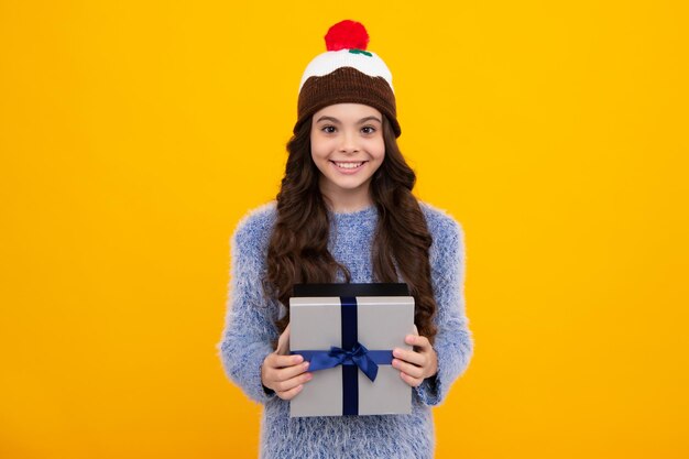 Funny kid girl in winter wear holding gift boxes celebrating happy new year or christmas winter holiday happy teenager positive and smiling emotions of teen girl