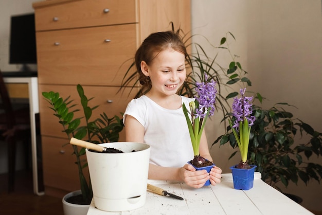 Funny kid girl with a bright blooming plant in a pot