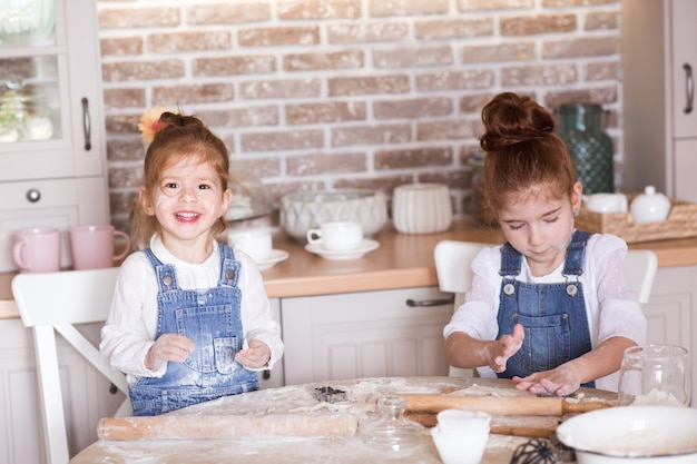 Funny kid girls making ginger bread in kitchen