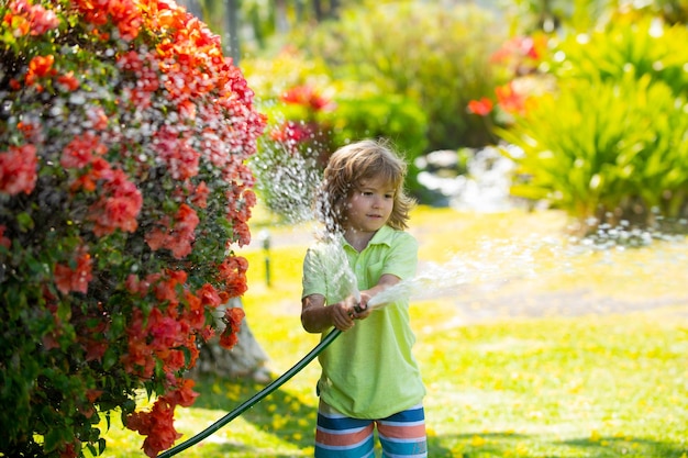 Funny kid playing with garden hose in backyard child having fun with spray of water summer outdoors