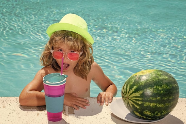 Funny kid in swimming pool Child drink cocktail summer fruits watermelon Summer cocktail for children