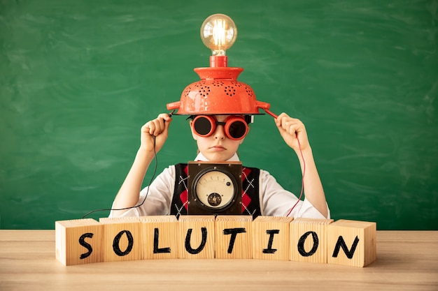 Photo funny kid with light bulb against green chalkboard wall.