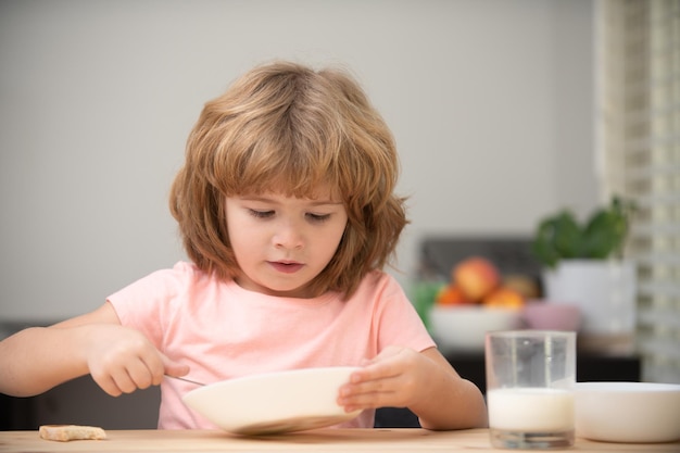 Funny kid with plate of soup. Child eating dinner.