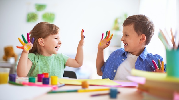 Bambini divertenti mostrano ai loro palmi la vernice dipinta.