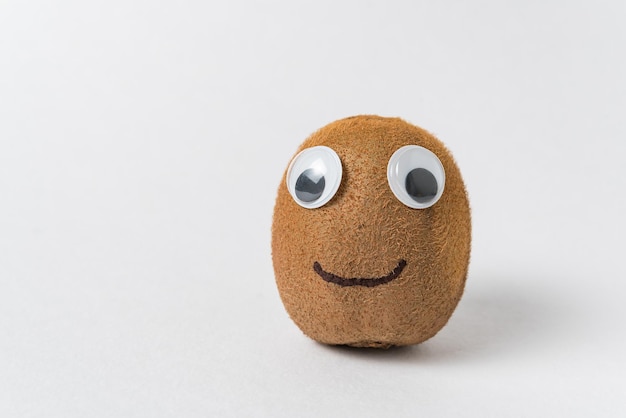 Funny kiwi fruit with Googly eyes and smile on white background Kiwi character