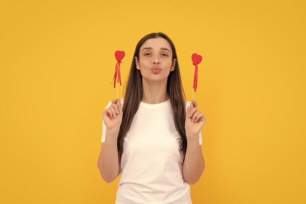 Funny lady in white shirt blow kiss with heart on yellow background womens day