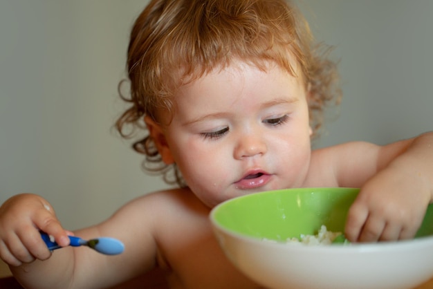 Funny little baby in the kitchen eating with fingers from plate healthy nutrition for kids