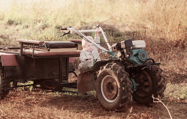 Funny little boy on walk-behind tractor in field