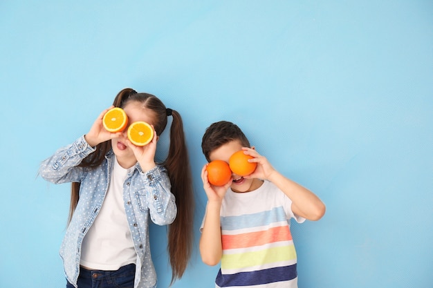 Funny little children with citrus fruit on color