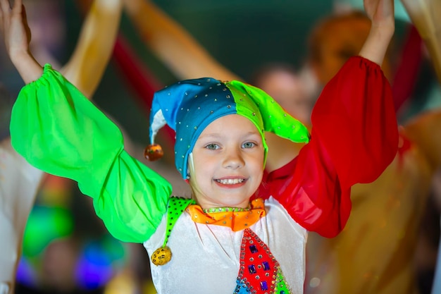 Смешная маленькая девочка в костюме клоуна танцует
