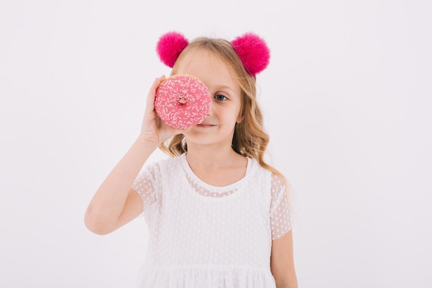 흰색 바탕에 도넛을 먹는 재미있는 어린 소녀