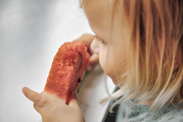 Funny little girl eating watermelon closeup