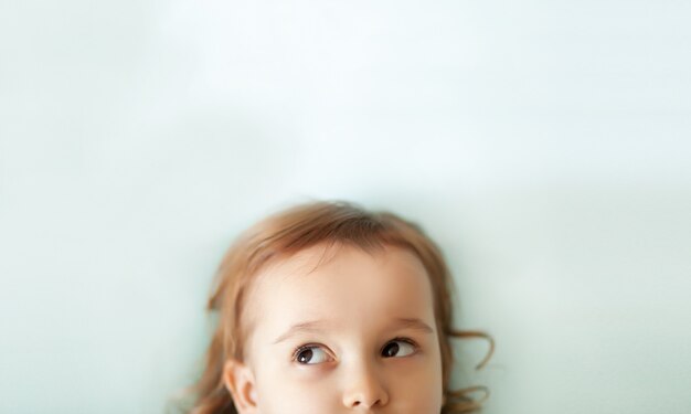 Funny little girl looking up on a white background